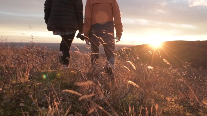 man and woman walking through grass in iceland during beautiful sunset