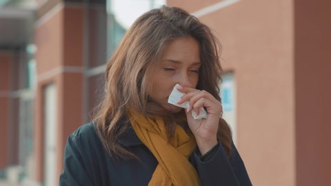 Sick young woman stand sneezing coughs feel sick at outdoor fever cold allergy city beautiful disease female nose lady runny tissue air pollution adult illness district slow motion