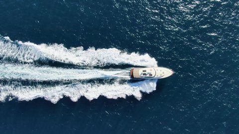 Stunning aerial 4k cinematic high angle drone footage following a powerful luxury high speed yacht rushing through deep blue ocean water near Manly Beach, Sydney, New South Wales, Australia.