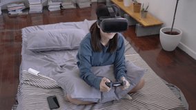 Asian teenage girl playing video game happy and exciting emotion at home. Using joystick and vr headset controlling game. Concept of education, technology, entertainment and virtual reality system.