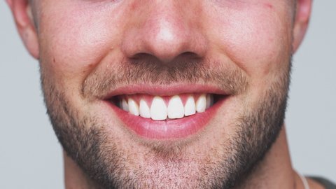 Close Up Of Mouth As Man With Perfect Teeth Smiles At Camera In Studio