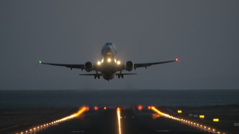 A frontal takeoff at night - we see an illuminated airstrip and a blinking plane, riding to the camera and finally taking off