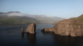 Aerial drone video flying over Drangarnir and Tindholmur sea stacks in Atlantic ocean, Faroe Islands. UHD 4k footage