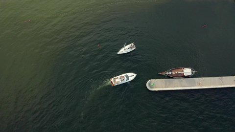 Aerial view of a white motor yacht. Yacht enters the bay in the parking lot. Gdynia, Poland. Many different yachts, catamarans moored to piers. Drone shot 4K.