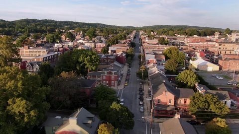 Cinematic drone aerial tracking street in small town America neighborhood community at sunset