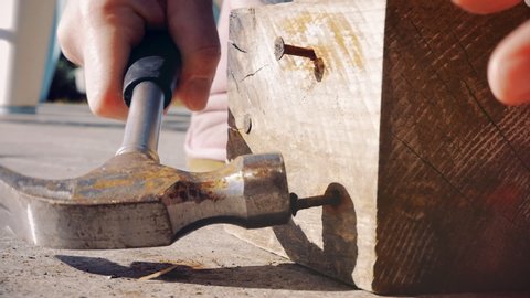 Woman hitting with hammer on wood closeup