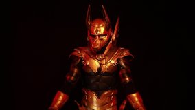 4k video clip, on a black background, a male actor in a suit of an Egyptian mythology character, the golden deity Jackal Anubis, twists buugeng in red light.