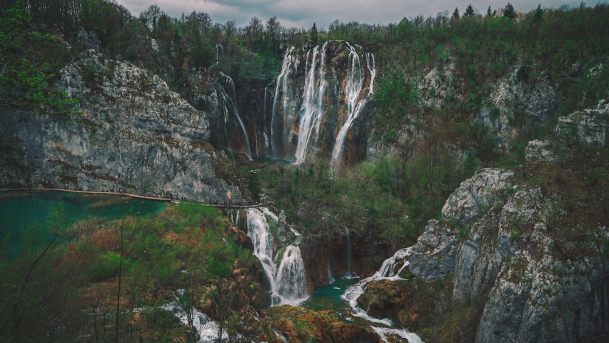 4k UHD Cinemagraph of fresh blue water flowing down beautiful waterfalls between a wooden foot bridge in the famous Plitvice National Park in Croatia, where the classic Winnetou movies were filmed. | Shutterstock HD Video #1037886944