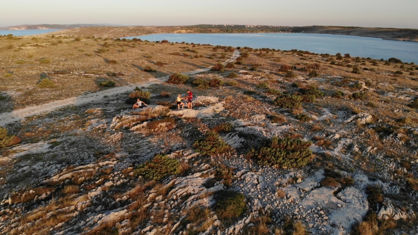 Family of four in sunset climbing on rocks and caring for children with beautiful vistas in the background