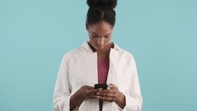 Beautiful casual african american girl using cellphone over blue background