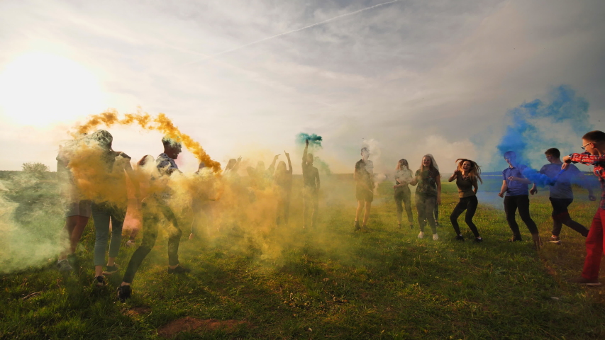 Happy friendly friends run across the field with toy planes that emit colored smoke. | Shutterstock HD Video #1037889725