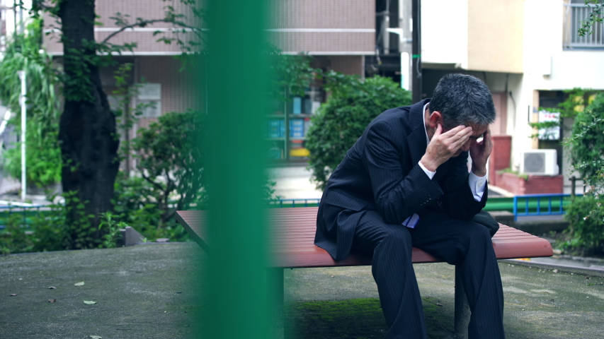 Depressed asian businessman sitting on a bench. Royalty-Free Stock Footage #1037891954