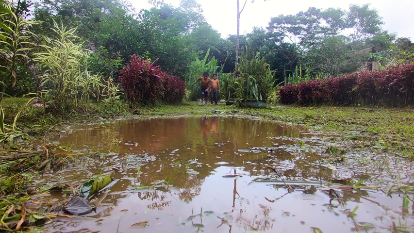 indigenous child throwing himself in a puddle of water in ecuador