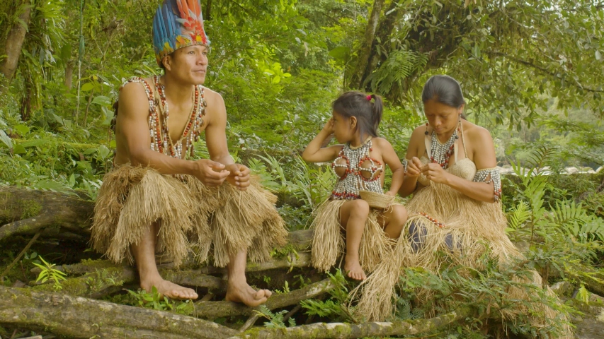 amazonian indigenous man telling a story to his family at the edge of a river in ecuador