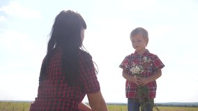 happy family concept slow motion video. happy mother's day! baby son congratulates mother on holiday and gives flowers. boy son gives girl mom lifestyle bouquet of wildflowers sunlight nature