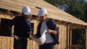 teamwork. concept building constructing architect slow motion video. two men builder in helmets study the house plan. two architects working on the construction of a frame house business contrast at