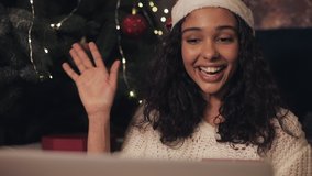 Close Up of Young Pretty Woman in Santas Hat Having Video Chat on her Laptop at Home near Christmas Tree Showing Christmas Present Box to Camera New Year and Christmas Celebration Concept