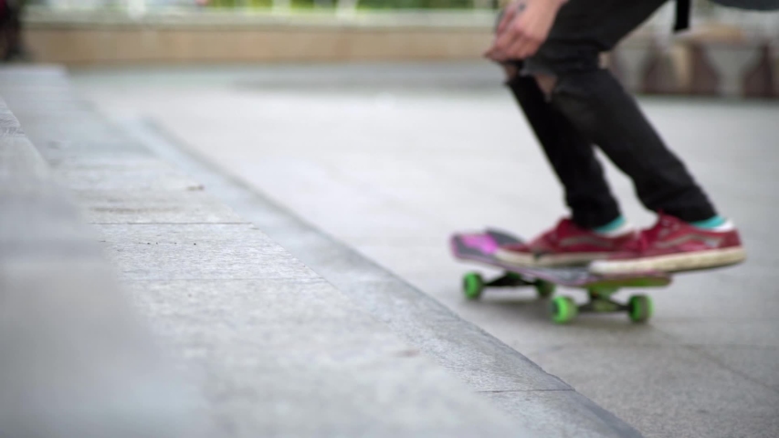 A guy on a bright, colored skateboard, tries to harness onto a concrete staircase and falls.Blurred focus. Royalty-Free Stock Footage #1037904599