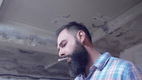 attractive bearded caucasian guy smokes a cigarette and drinks coffee from a metal cup indoors. 4k. 4k video. slow motion. 24 fps