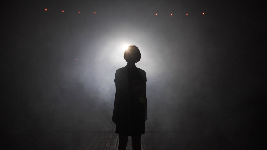 black silhouette of young woman walking to light spot through fog clouds and hand hides bright disk slow motion Royalty-Free Stock Footage #1037908364