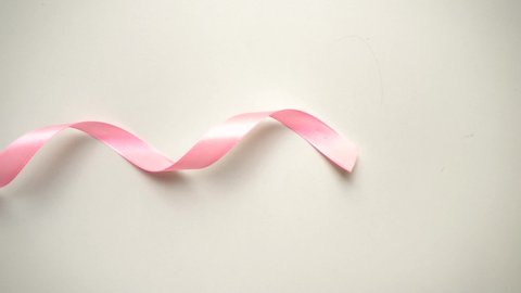 Symbol of world breast cancer awareness month in october . Pink silk ribbon over white background.