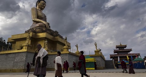 The Buddha Dordenma statue on the hills around Thimphu, Bhutan, Himalaya. Time lapse at the kingdom of Bhutan. The golden Buddha during a prayer ceremony for the Thailand king in 2017. Monk passing by