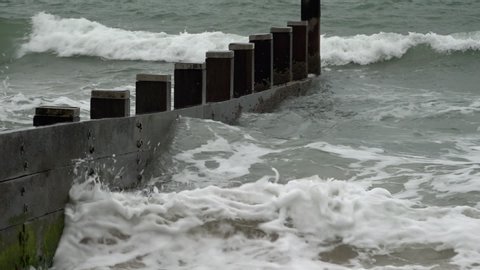 UK September 2019 - Waves break in slow motion against a wooden groyne.