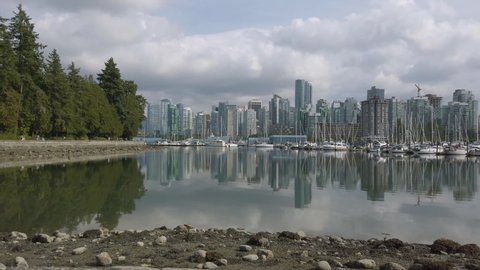 August17,2019:Vanvouver,Canada: Landscape view of the city center of Vancouver in Canada with many yachts in Vancouver Harbour-View from Stanley Park and reflection of the city on the lake surface