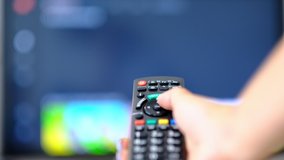 slow motion woman watches TV and presses a button on the remote control. hand holding the TV remote control and turn off smart tv. Channel surfing. blurred background