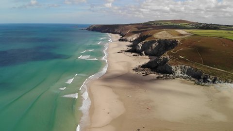 Cinematic drone and aerial footage over Porthtowan Beach in North Cornwall. Green seas and blue skies and surfers enjoying the waves