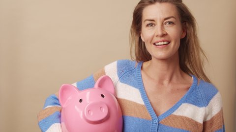 Medium Shot Of Woman Holding Large Piggybank And Smiling To Camera