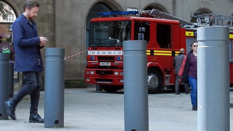 Manchester / United Kingdom (UK) - 09 14 2019: Fire service engine truck parked as fireman sets up tape barrier in city centre street as pedestrians pass.
