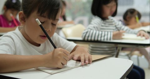 Asian children study and writing the classroom at school together. Concept of education.