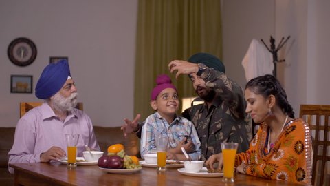 Happy Indian Sikh family - Father as Army officer. Fun time at the dining table during breakfast. Happy big family having food together and father playing with his son. Laughing and spending qualit...