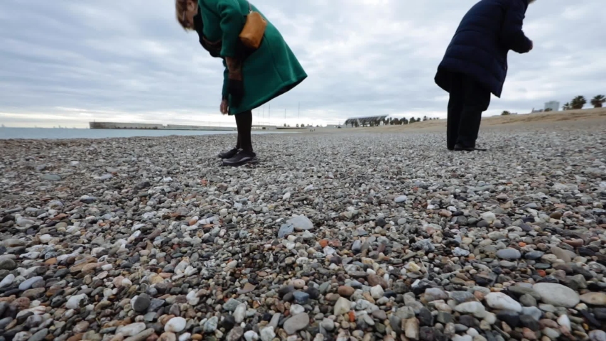 Mature couple picking rocks by the sea