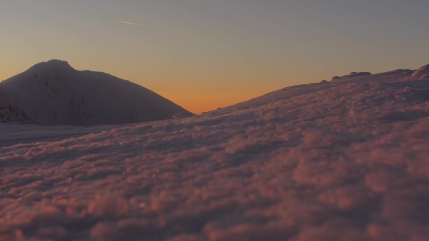 Lockdown shot of hiker snowshoeing on snowcapped mountain during sunset