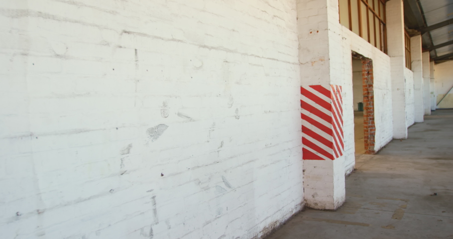 Front view of a young Caucasian man wallriding on a BMX bike in an abandoned warehouse