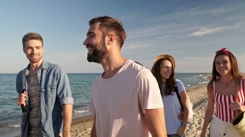 Group of young smiling friends talking and walking on the beach near the sea Royalty-Free Stock Footage #1037938235