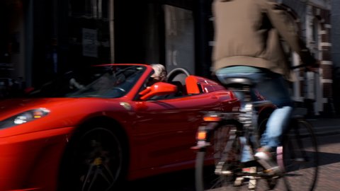 ZWOLLE, THE NETHERLANDS, SEPTEMBER 14, 2019: Ferrari F430 Spider sports car driving in a street in the city of Zwolle during a sunny summer morning. People in the background are looking at the cars.