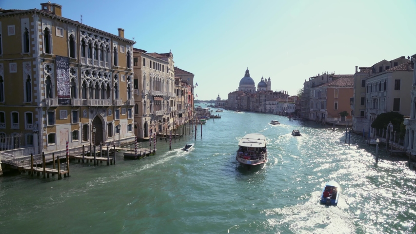 Boats float on one of many back canals in Venice Italy as tourists roam the narrow streets