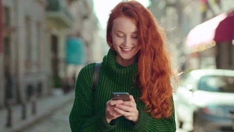 shot on Arra Alexa Mini Attractive young red hair woman walking down the street smiling using phone chatting with friends looking around positive emotion