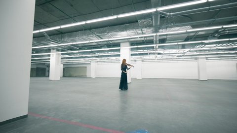 Female musician is playing the violin in an empty hall