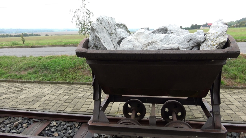 Old mining trolley minecart loaded with stones stands on rails
