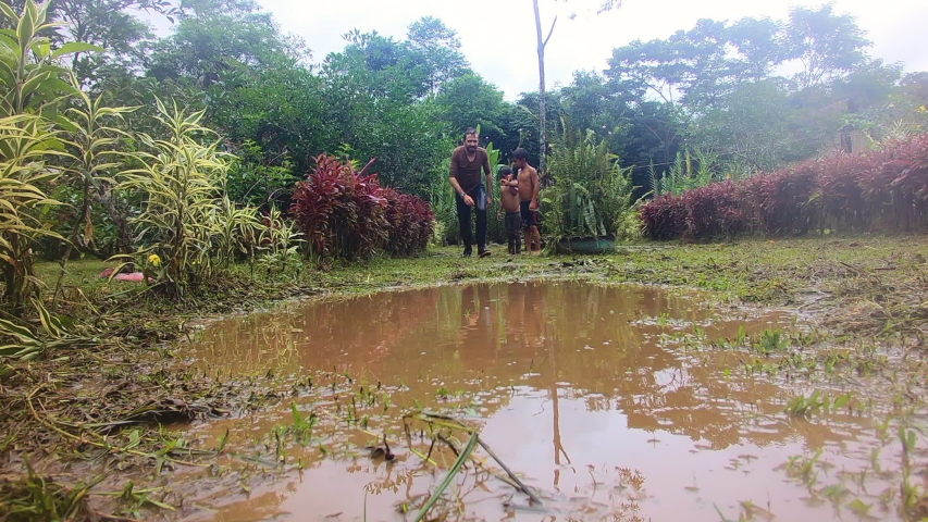 caucasian adult man playing with indigenous children in a puddle in an amazon village slow motion
