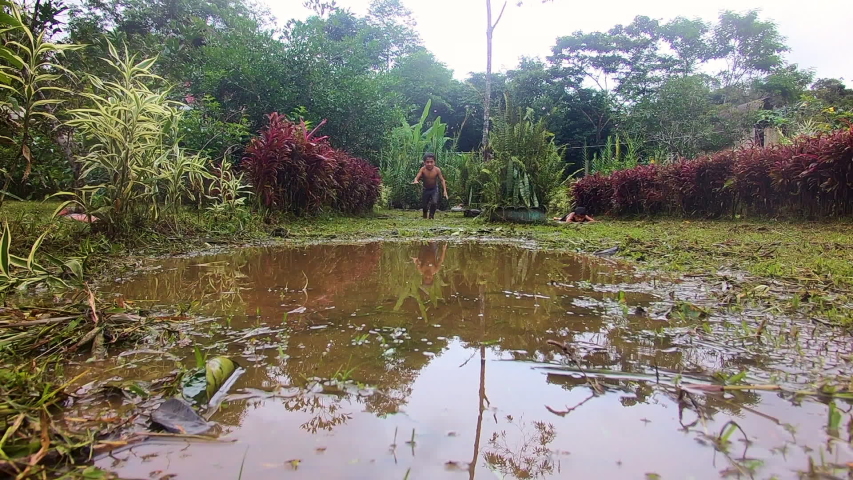 indigenous kid throwing himself into a puddle in an amazon villageslow motion
