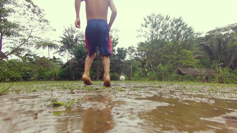 indigenous kids playing soccer in the rain in a village in the amazon rainforest