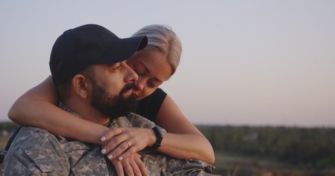 Medium close-up of wife hugging wheelchaired soldier husband