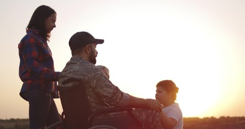 Medium close-up of a wheelchaired soldier hugging his daughter