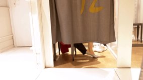 female legs are visible from under the curtains in the fitting room of a clothing store. - Powered by Shutterstock - Get 15% off with code: PIKWIZARD15