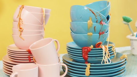 Kitchen table is full of dirty dishes, isolated yellow background. Studio shot.